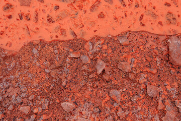 A winter ice puddle in a severe frost. Red oxidized soils with puddles in winter