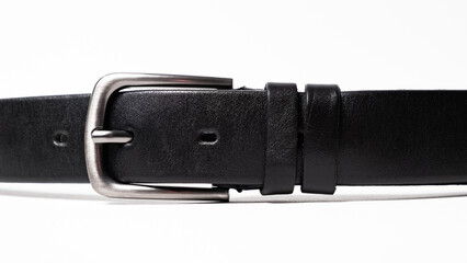 Black Classical leather Belt isolated on white background close-up. Fastened fashionable unisex accessory with dark chrome matted metal buckle. Man lux strap. Haberdashery goods. Minimalistic style