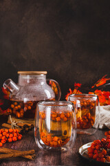 Tea with rowan berries in glasses and a teapot on the table vertical view