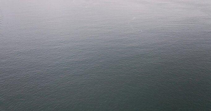 Aerial drone shot of motorboat passing by the Jeronimos Monastery and Discoveries monument on the waterfront in Lisbon, Portugal, Europe. Drone orbiting and descending. Shot in ProRes 422 HQ