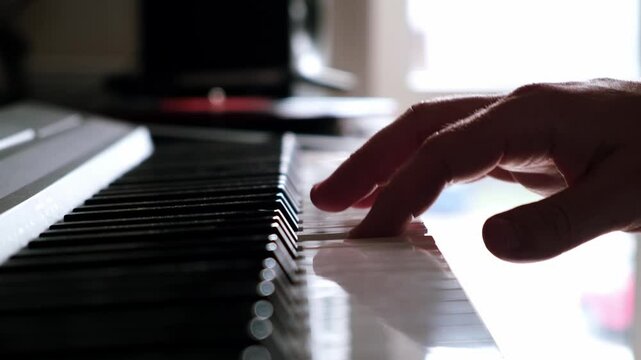 One right man's hand playing a piano. Music lesson. Musical education. Musician hobby for adult. A player picks out a melody on a synthesizer. Unrecognizable person. Soft focus. Side view of keys. 4k