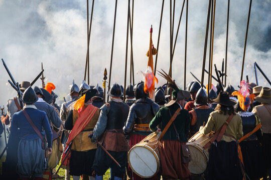 Drummers strike the charge in front of a group of pikemen with long sticks. Dutch historic field siege. Dutch revolution cosplay