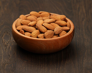 Shelled almonds filling a wooden bowl on a rustic table