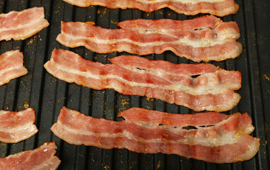 Close up cooking bacon slices on electric grill