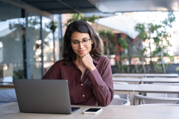 Portrait of 20s latin hispanic freelance business entrepreneur. Smiling businesswoman working remotely online on laptop computer outdoors. Smiling Indian young student woman using pc app for learning