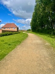 Bright sunny summer background with earthen road, poplars, village houses, white clouds  and a child on a bicycle