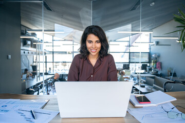 Young businesswoman professional employee using pc doing online banking analysing at workplace. Latin hispanic middle age business woman working on laptop computer in modern office. Banner, copy space