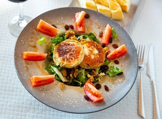 Appetizing salad with goat cheese, tomatoes and walnuts on a plate