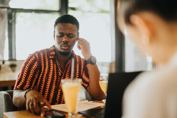 Diverse group of people collaborating in a casual meeting at a coffee bar, featuring laptops and drinks on the table.