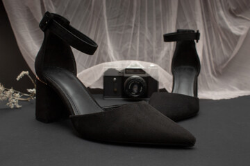 Black heel shoes with black background and matching accessories.