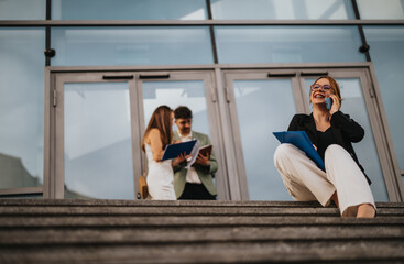 Three business professionals engage in a discussion outdoors, while a woman happily talks on the phone in the foreground.