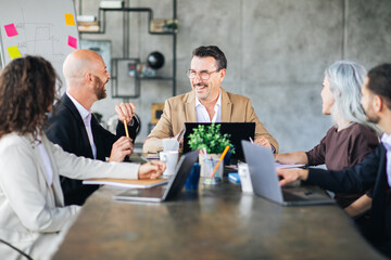 A group of professionals engaged in a lively discussion around a conference table in a contemporary office. Each member contributes ideas with enthusiasm, fostering collaboration.