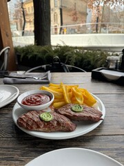 Grilled Steak with Herb Butter, Crispy Fries, and Tomato Sauce on a Rustic Outdoor Table