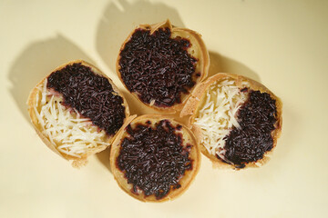 Martabak mini or terang bulan mini is Indonesian popular street food, made from flour, egg, yeast, topped with cheese or chocolate. Mini sweet martabak isolated on yellow background.