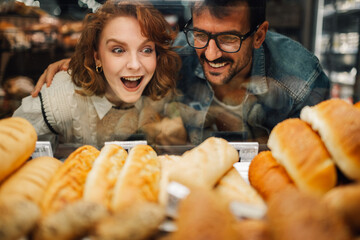 Happy couple choosing bread in supermarket bakery display