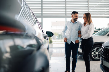 Couple looking at cars in showroom, indicating interest in purchase
