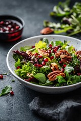 Freshly prepared salad with greens, pecans, and cranberries on a marble table at a cozy setting
