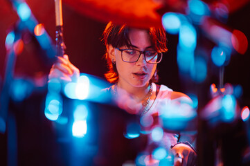 Drummer playing with passion on stage under colorful lights