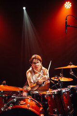 Drummer performing live on illuminated stage with drum kit