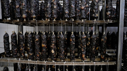 Sausages hang on a rack in a smokehouse. Homemade sausage production.