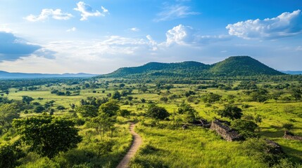 Full view of an ancient Khmer stone castle in Cambodia, surrounded by lush greenery and rolling hills under a vibrant blue sky