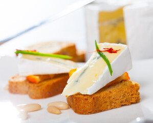 Tasty crostini with blue cheese, orange, decorated with chives and pine nuts