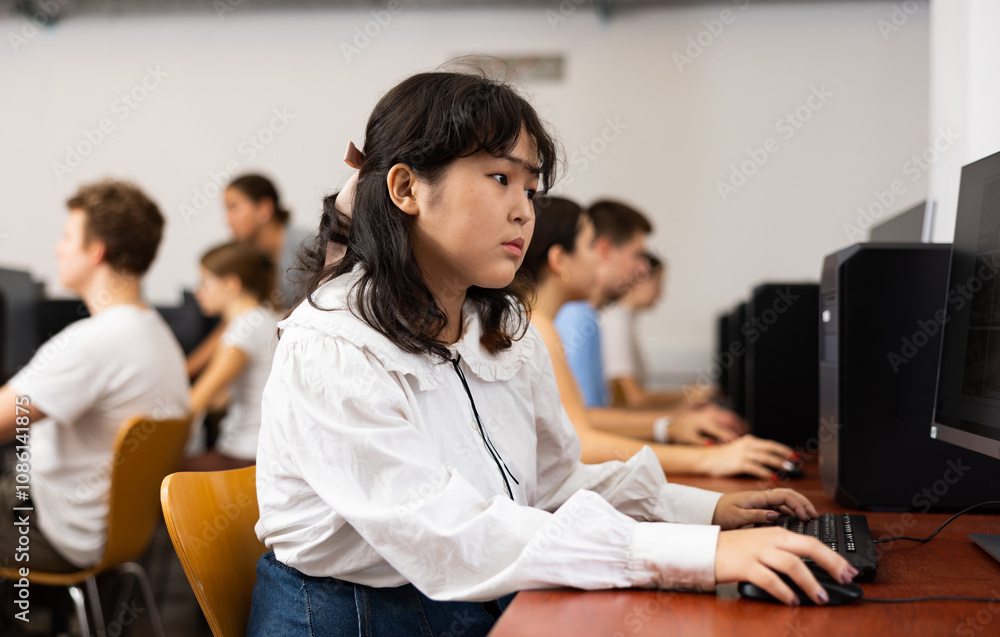 Poster smart asian female teenager learning computer science while she is using a pc in the computer classr