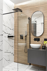 Modern interior of bathroom with ceramic wash basin with black faucet , wooden brown striped tiles on the wall and mirror. Luxurious hygiene room in industrial style with shower and glass. Vertical.