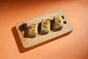 Banana bolen is made from banana peels and dry cakes and filled with chocolate and cheese. Served on a wooden plate. Selective focus image.