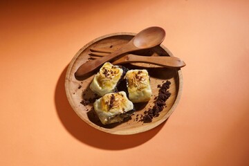 Banana bolen is made from banana peels and dry cakes and filled with chocolate and cheese. Served on a wooden plate. Selective focus image.