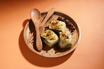 Banana bolen is made from banana and pastry skin and has chocolate and cheese filling. Served in wooden plate. Selective focus image.