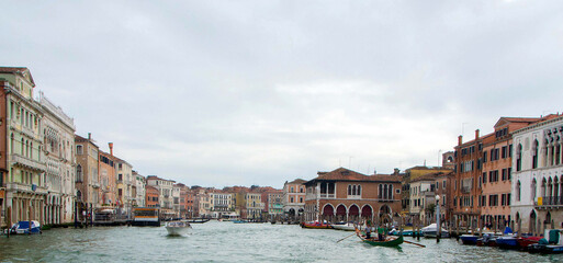 A view of historic Venetian buildings along the Grand Canal, showcasing classic Italian architecture. The iconic canal waters reflect the facades, with boats and gondolas adding to the charm of Venice