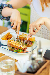 woman enjoying a delicious sandwich with roasted meat and fresh greens at a bustling cafe during lunch hour