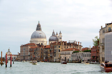 Naklejka premium A view of historic Venetian buildings along the Grand Canal, showcasing classic Italian architecture. The iconic canal waters reflect the facades, with boats and gondolas adding to the charm of Venice