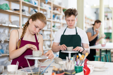 Students teenage girl and teenage boy sculpt ceramic product from raw clay in workshop