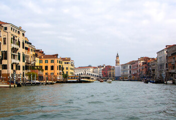 A view of historic Venetian buildings along the Grand Canal, showcasing classic Italian architecture. The iconic canal waters reflect the facades, with boats and gondolas adding to the charm of Venice