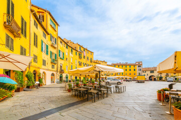 Sidewalk cafes and shops inside the colorful circular Piazza del Anfiteatro, the ancient amphitheater in the medieval old town of Lucca, Italy.