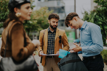Group of business professionals gathered outdoors, engaging in a strategic discussion and review. The image captures a relaxed yet focused atmosphere, highlighting teamwork and planning in a dynamic