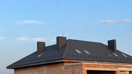 Metal tile roof. Three chimneys in one house