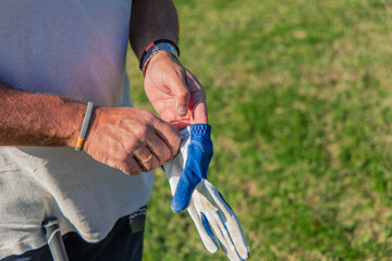 closeup of senior golfer adjusting glove before starting golf game