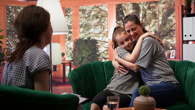 Proud mother accepting her daughter as she is at therapy session, expressing her unconditional love and tenderness. Mom and adolescent bonding together in counseling, acceptance. Camera B.