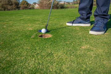 copyspace Close-up of golfer's feet striking the ball with a putter toward the hole on the green