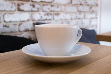 On the table stands a white porcelain cup on a saucer, harmoniously fitting into the minimalist composition.