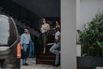 Business people gathered outside near stairs, engaging in a conversation. They appear confident and focused, holding documents and wearing smart casual attire, suggesting a collaborative meeting.