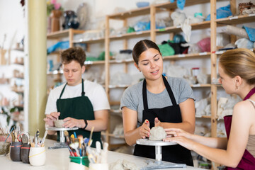 Potter teaches teenagers how to make pottery out of clay in a workshop