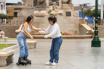 Young woman helping her friend learning to skate in a city park