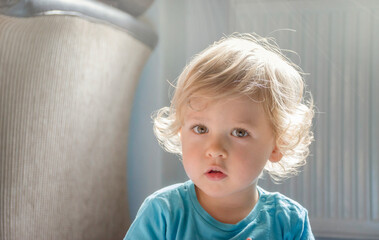 Sweet little child boy portrait sitting on the floor at home, beautiful morning light