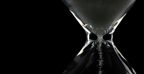 Close up of white Sand Hourglass over black background. Sand through time hourglass fall down as...