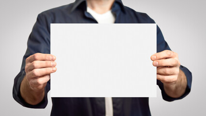 Coronavirus Quarantine. Man In Mask Holding Paper With Inscription Stay Safe, Work From Home Standing Over Gray Background. Cropped