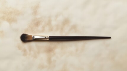 A single black makeup brush on a white background with soft brown stains.